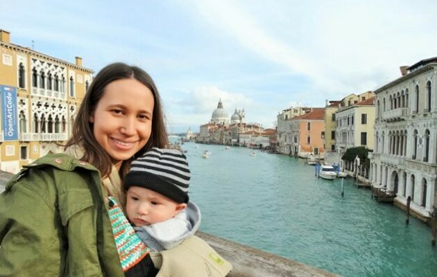 A woman holds her baby on a bridge in Venice Italy